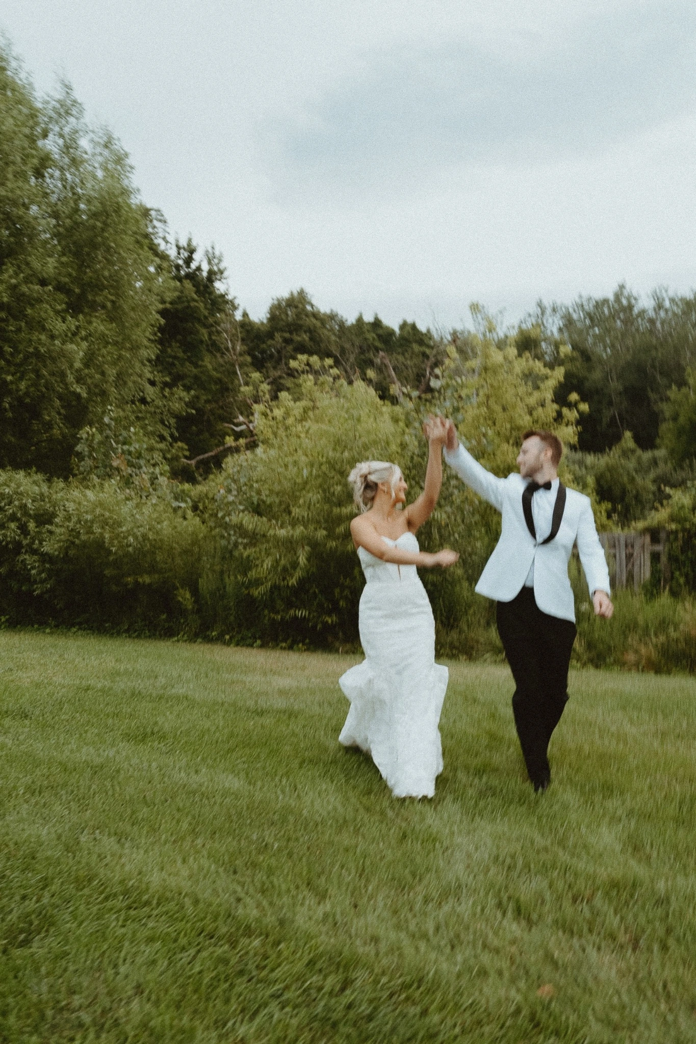 Newlyweds running together through a green field on film