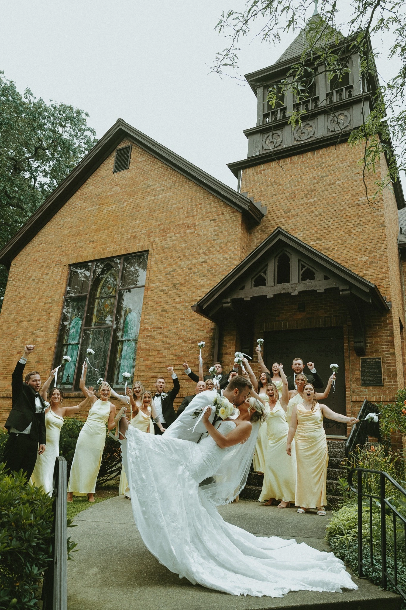 Wedding party celebrating with the newlyweds outside a character-filled church venue